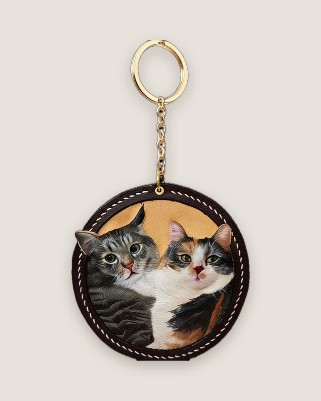 Two cats painted side by side on a round leather keychain